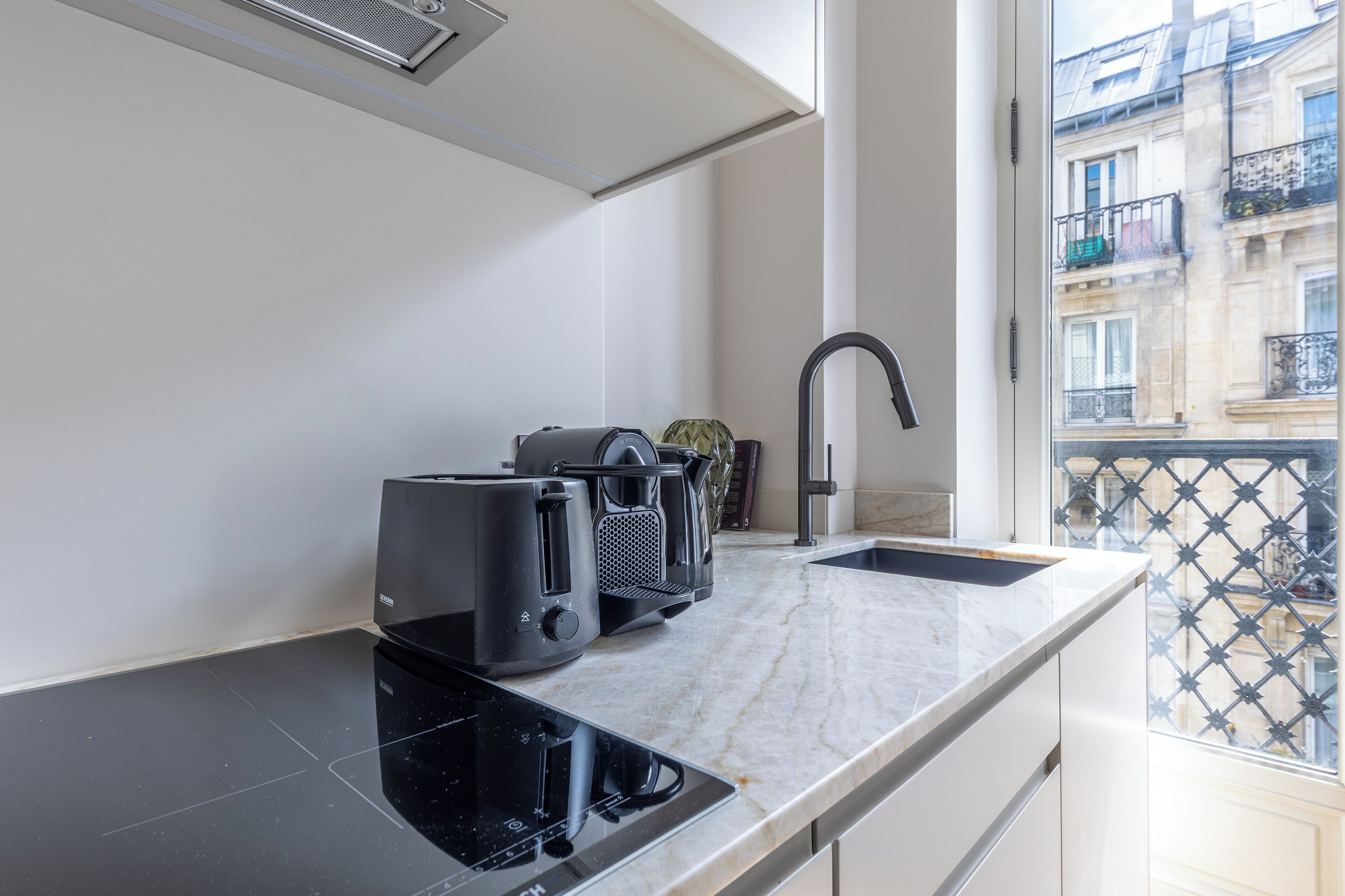 Une cuisine moderne dotée d’une plaque de cuisson à induction noire, d’un four encastré et d’une machine à café.