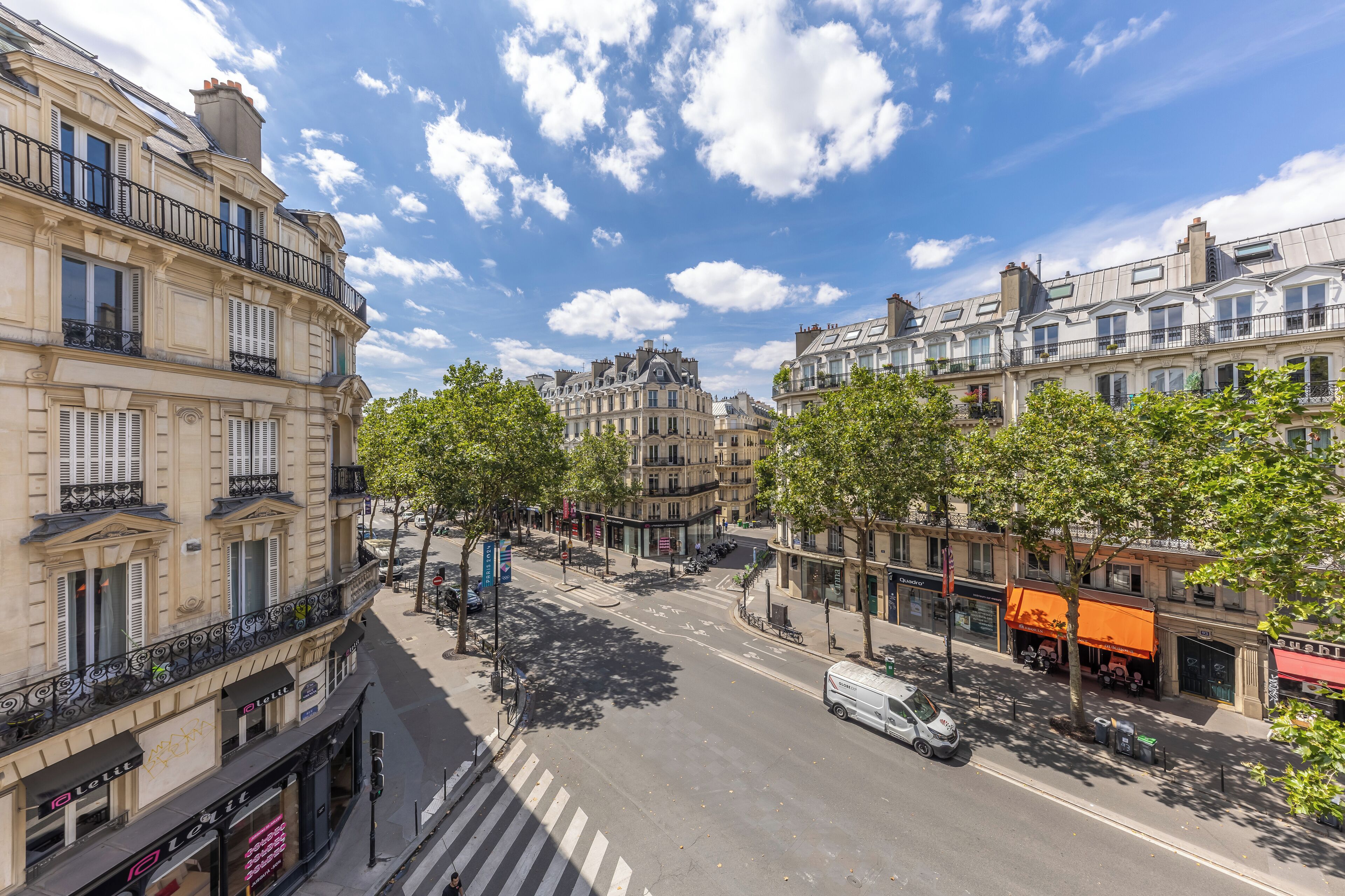A street view with buildings, trees, and a van.