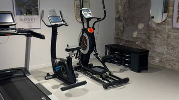 Un gimnasio en casa con cinta de correr, elíptica y bicicleta estática.