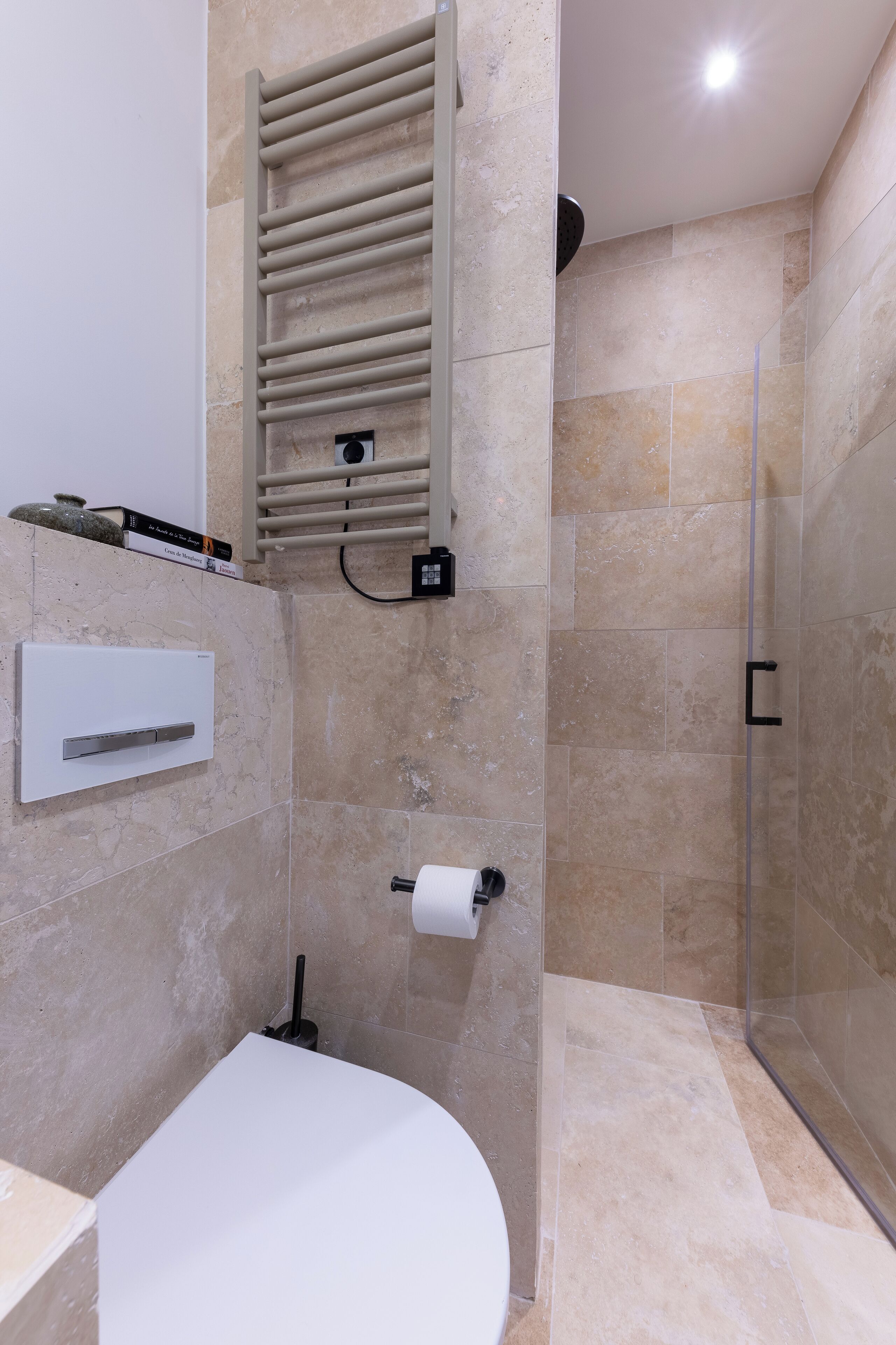 A modern bathroom with a toilet, a towel rack, and a shower area.