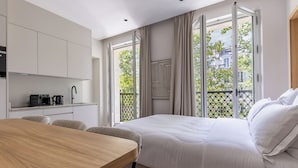 A modern hotel room with a large bed, a dining table, and a kitchenette. - Aparthotel Quartier Libre Marais (Paris)