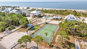 En fastighet vid kusten med flera hus, en tennisbana och en strand.