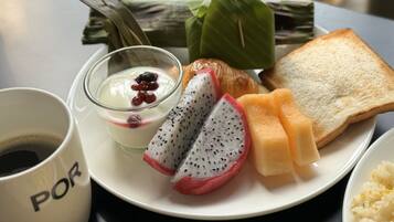 A plate with a cup of coffee, a bowl of yogurt with berries, slices of dragon fruit, a croissant, and a piece of toast.