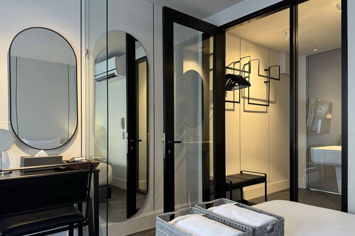 A modern bathroom with a large mirror, a vanity with a black countertop, and a white sink.