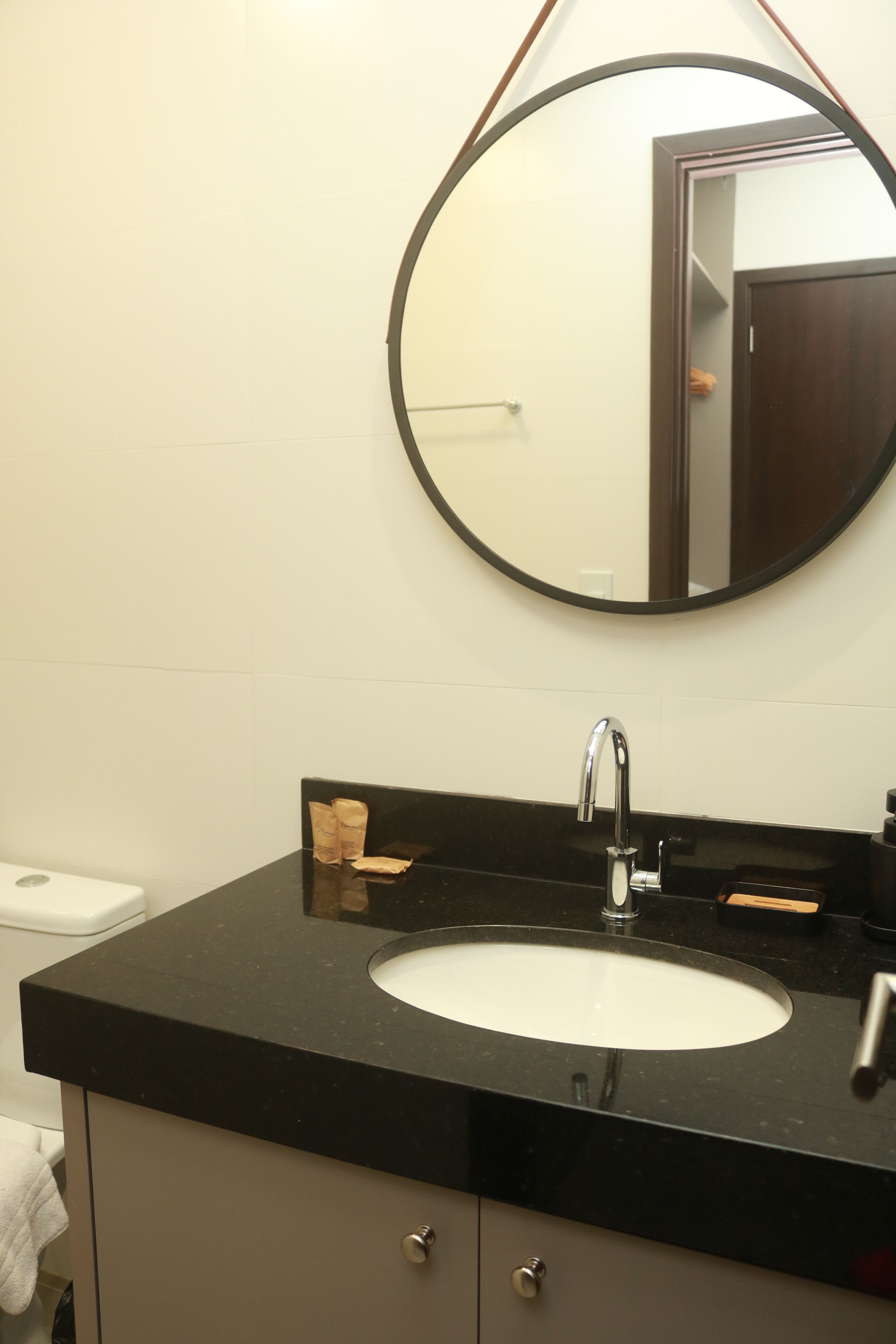 Ein Badezimmer mit rundem Spiegel, Waschbecken und Toilette.
