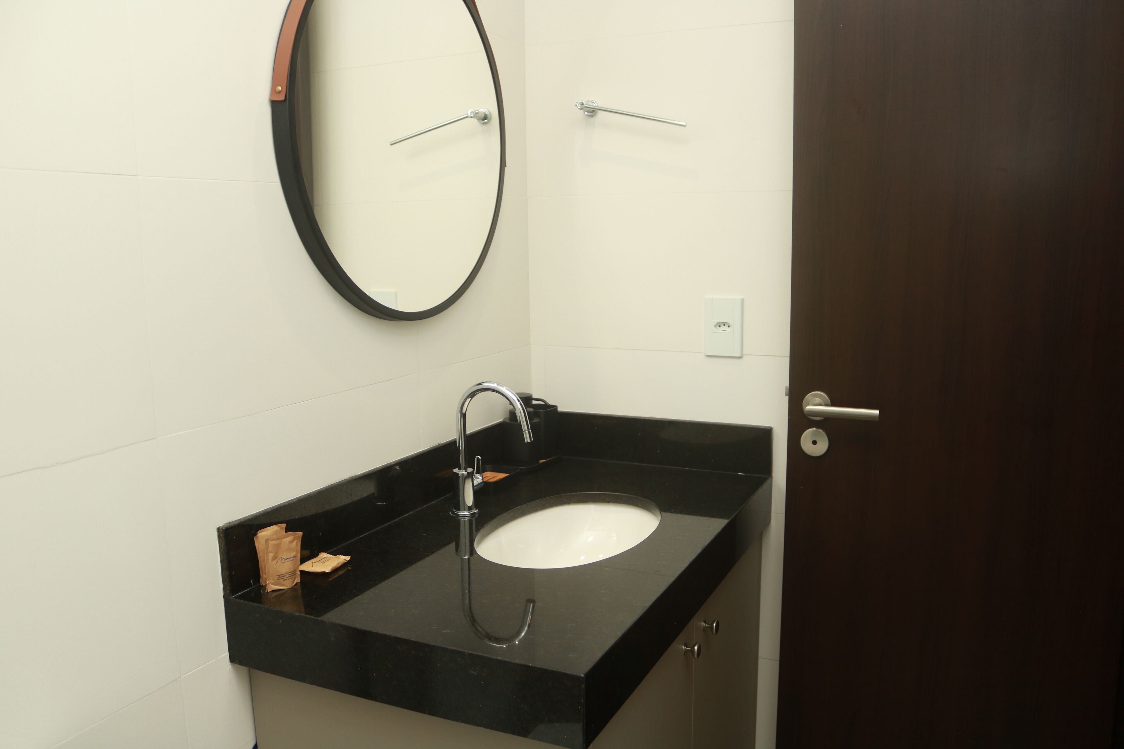 A bathroom with a black sink, a mirror, and a door.