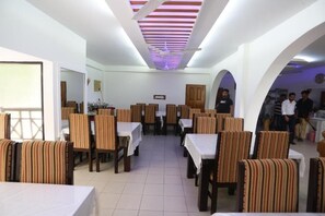 A dining area with tables and chairs, a ceiling fan, and a clock on the wall. - Nagar Valley Hotel Ltd. (Dhaka)