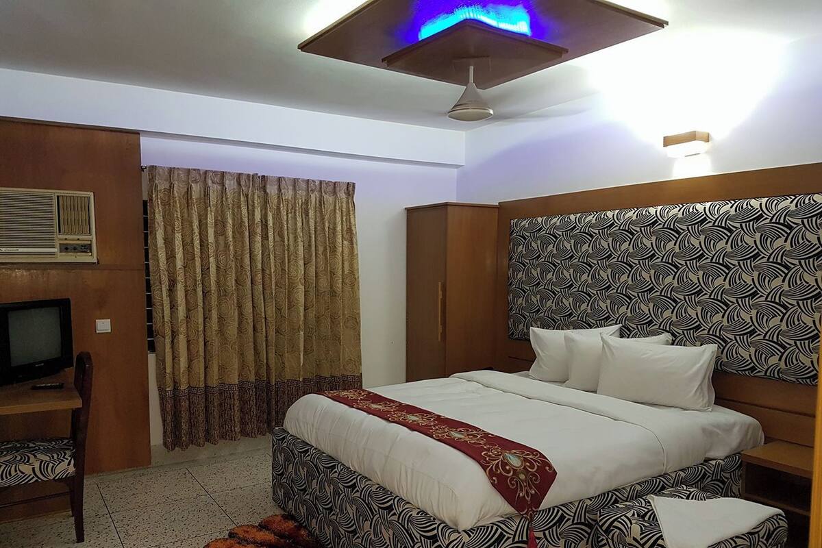 A hotel room with a bed, a television, a desk, and curtains.