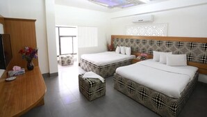 A hotel room with two beds, a wooden desk, and a decorative wall panel. - Nagar Valley Hotel Ltd. (Dhaka)