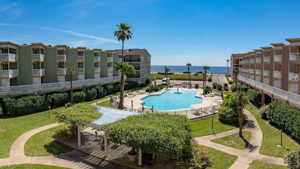 Un hôtel doté d’une piscine centrale, de nombreux balcons et offrant une vue sur l’océan.