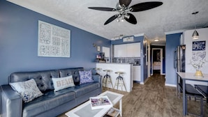 Un salon moderne avec un canapé bleu, une table basse et un ventilateur de plafond.