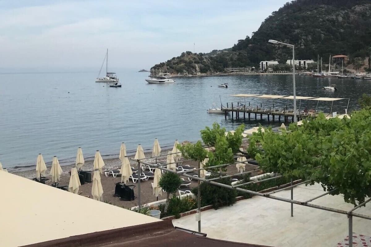 Une vue sur la côte, avec un port de plaisance, des bateaux et une colline parsemée de bâtiments.