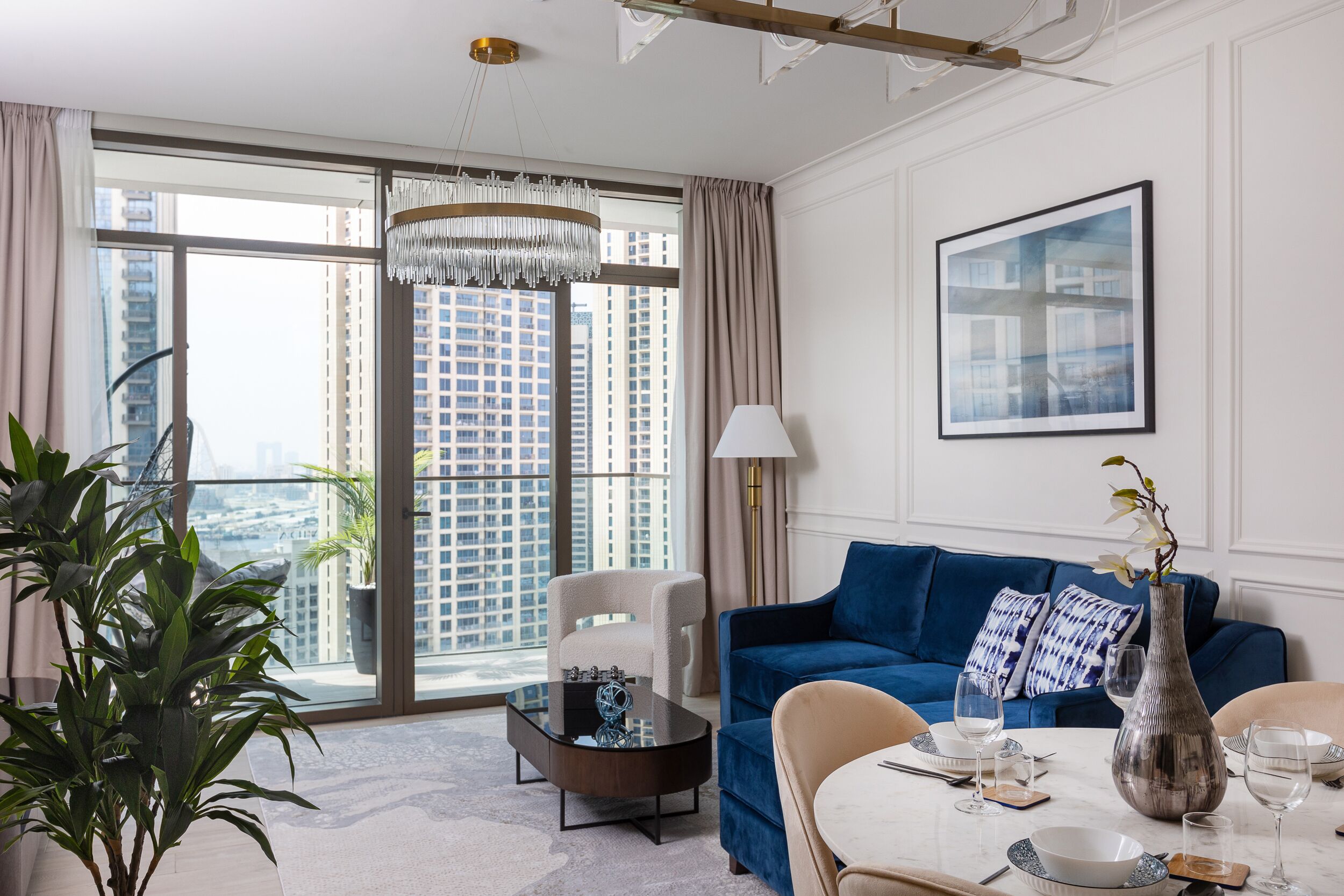 A modern living room with a blue sofa, a coffee table, and a dining table set for four.