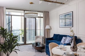 A modern living room with a blue sofa, a coffee table, and a dining table set for four.