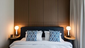 A hotel room with a large bed, two bedside lamps, and a wooden headboard.
