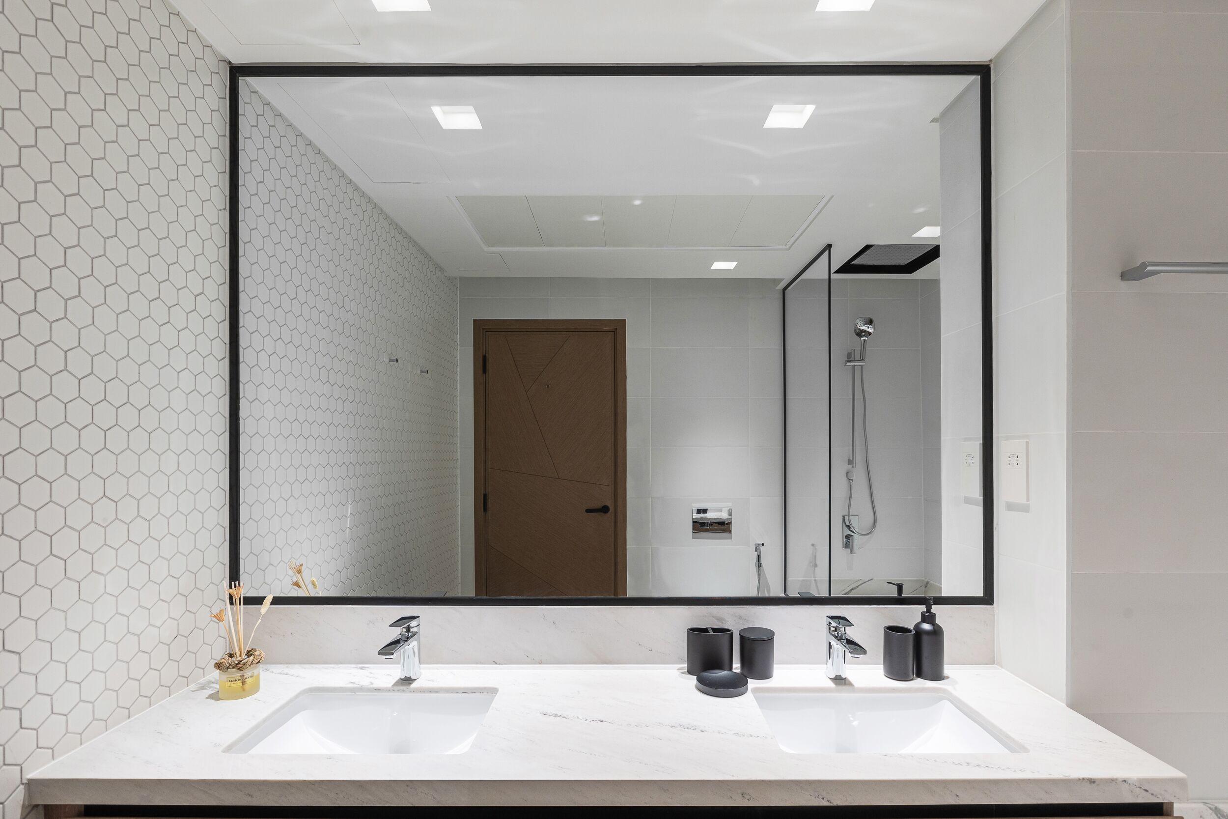 A modern bathroom with two sinks, a large mirror, and a shower.