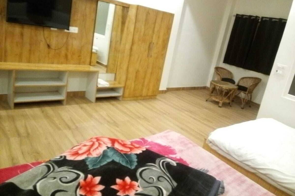 Una habitación con cama, escritorio, silla, televisor y ventana con cortinas.