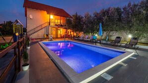 En swimmingpool med solstolar och en byggnad med en balkong.