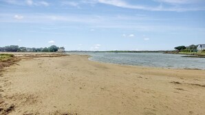 A wide sandy beach with a calm river, a few boats, and distant buildings. - Gorgeous apartment in Locmariaquer with WiFi (Locmariaquer)