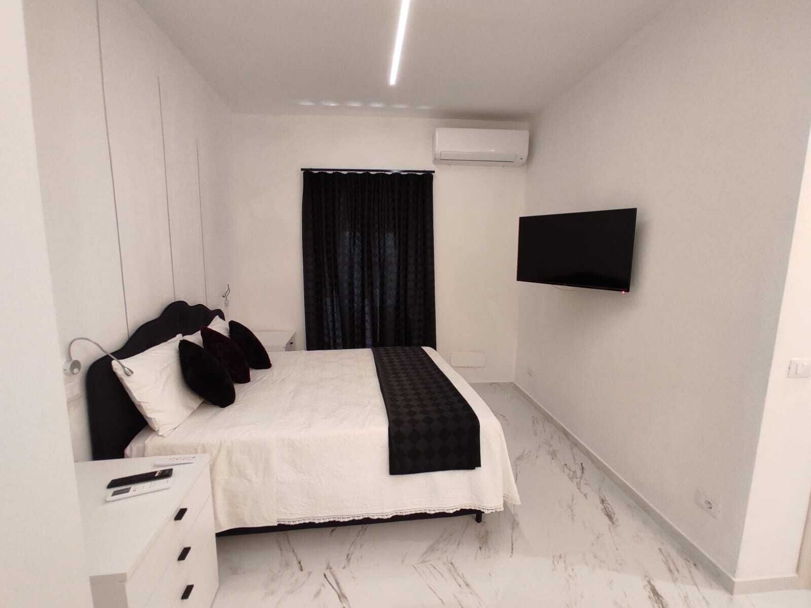 Ein modernes Schlafzimmer mit Bett, Flachbildfernseher und Klimaanlage.