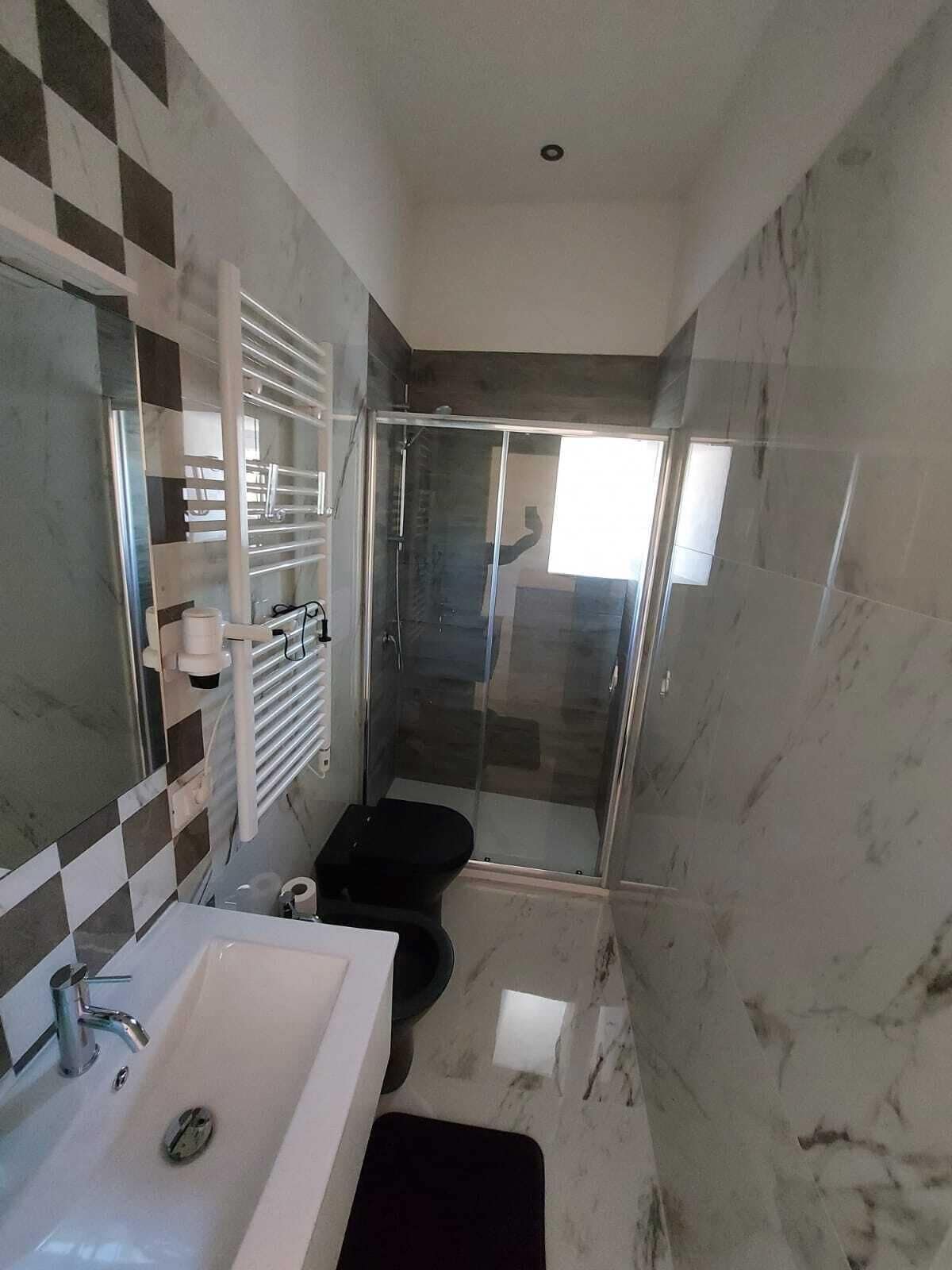 Un bagno moderno con uno specchio grande, un lavandino, un water e una cabina doccia in vetro.