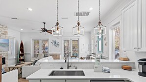 Una cocina moderna con una isla central, electrodomésticos de acero inoxidable e iluminación colgante.