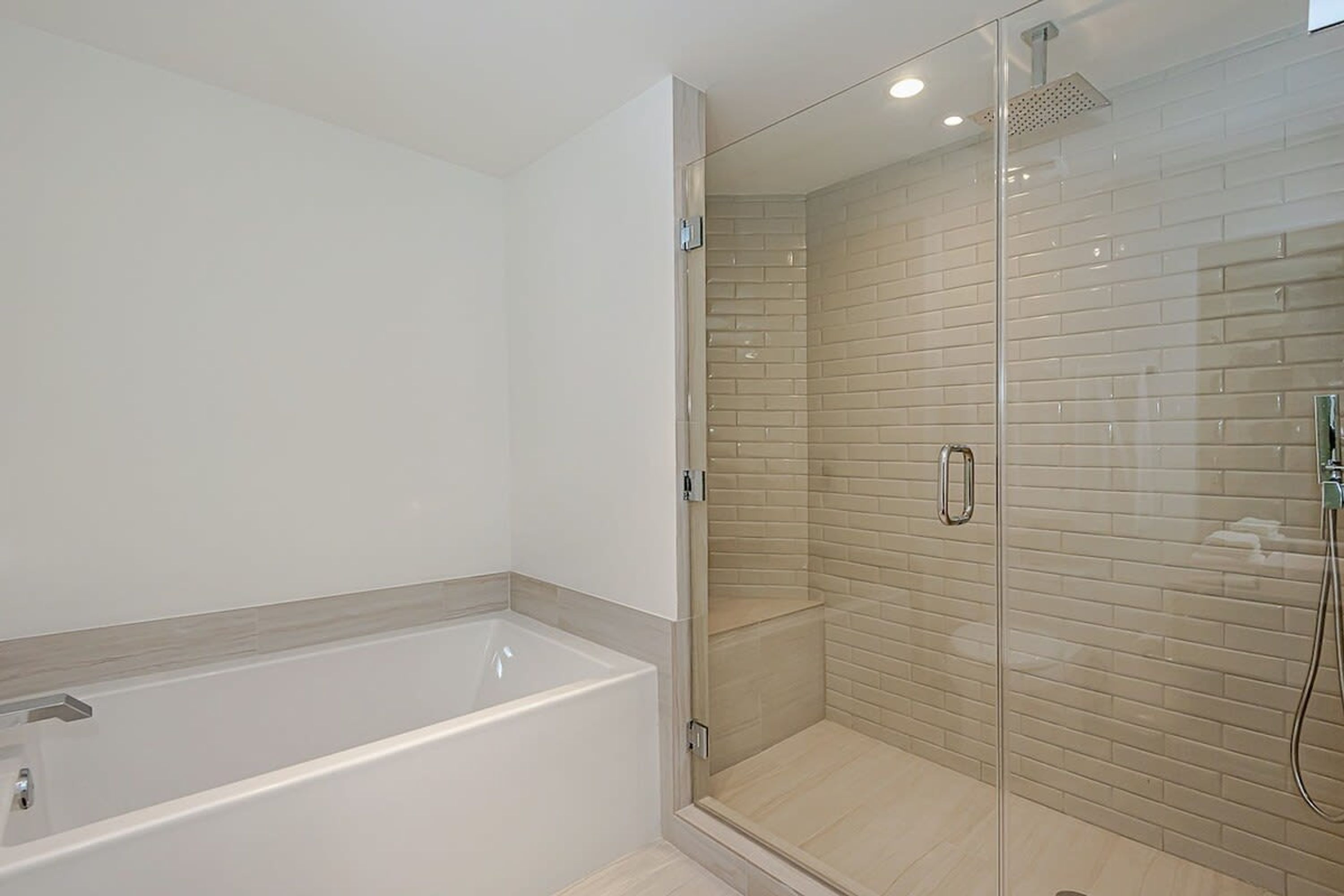 A modern bathroom with a glass-enclosed shower, a standalone bathtub, and a tiled shower area.