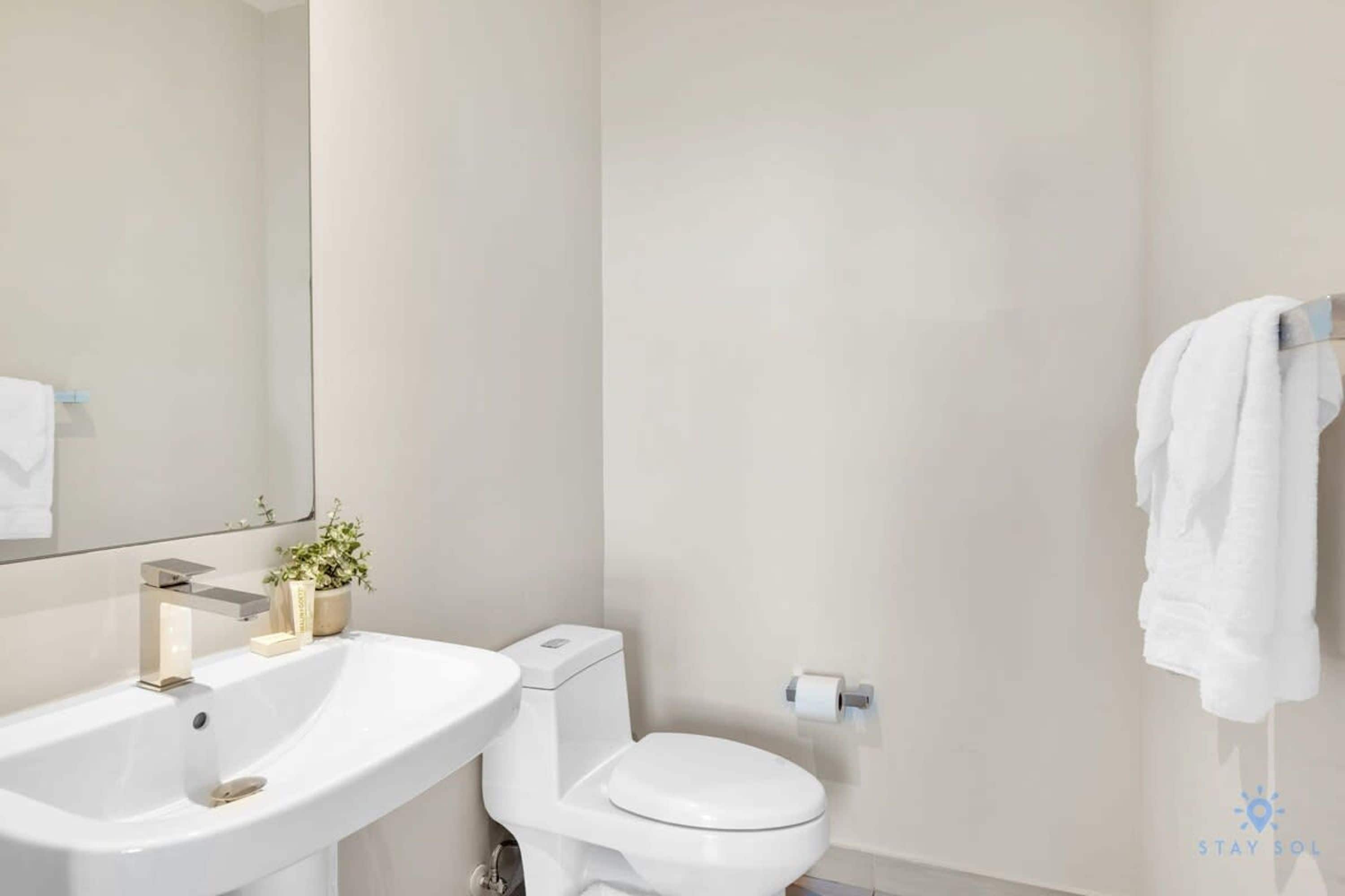 Une salle de bain avec un lavabo blanc, des toilettes et un porte-serviettes.