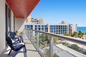 A balcony with a view of a coastal cityscape, featuring modern buildings and a clear sky.