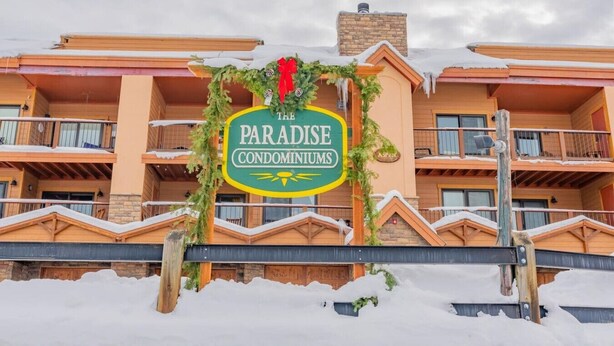 Een meerhoog gebouw met een bord waarop 'Paradise Condominiums' staat.