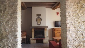 Una habitación de paredes de piedra con chimenea, televisor y un mueble de madera.