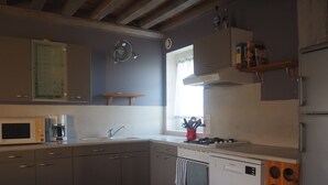 Una cocina moderna con armarios grises, microondas, cafetera, fregadero, estufa y lavavajillas.