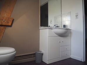 A bathroom with a white sink, mirror, and cabinet, a toilet, and a trash can. - Gîte de la Petite Maison, Entre Cabourg et Caen (Hérouvillette)