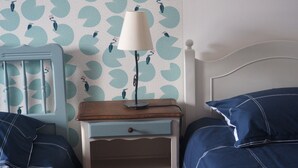 Un dormitorio con una cama, una mesita de noche, una lámpara y una pared con diseño de hojas.