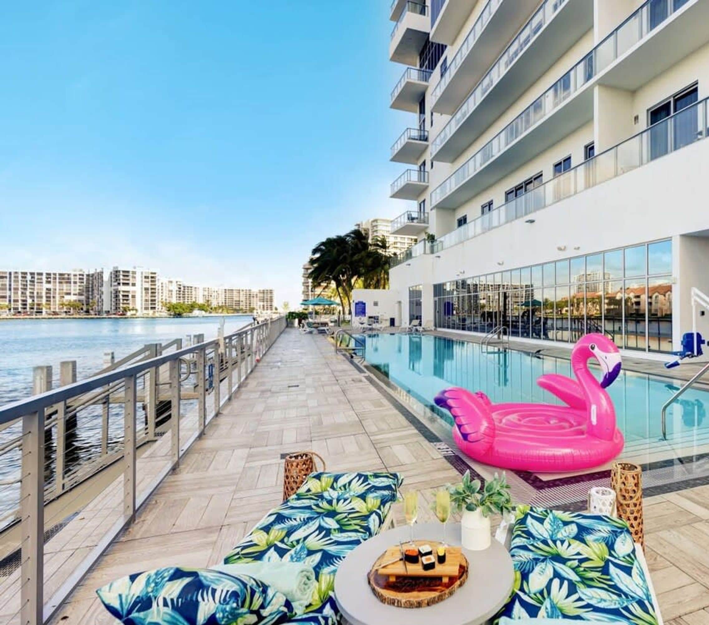 A pool area with a water slide, lounge chairs, and a pink flamingo float.