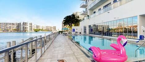 A pool area with a water slide, lounge chairs, and a pink flamingo float.