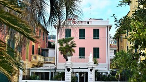 A pink building with a balcony and a statue in front. - Hotel Lido (Varazze)