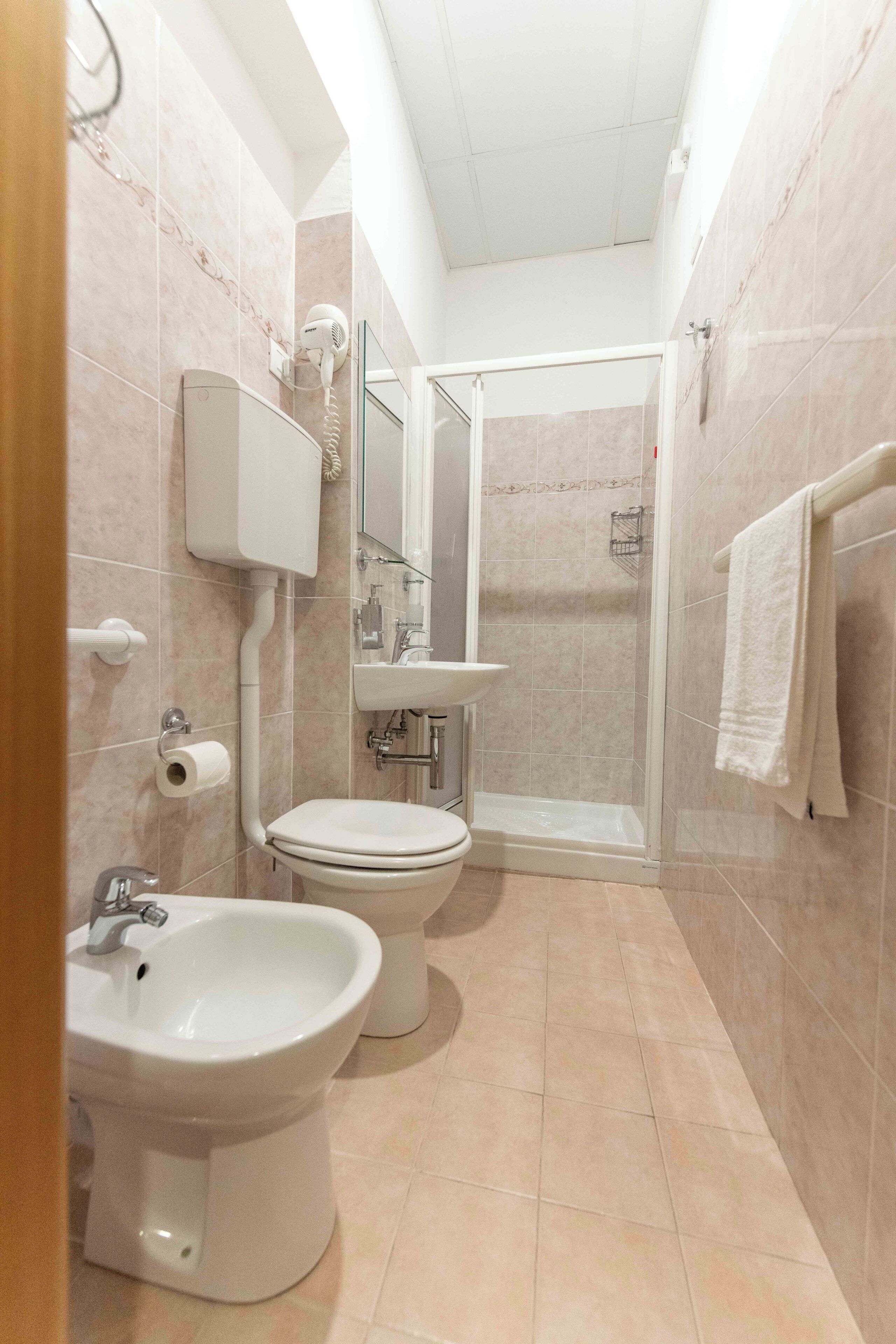A compact bathroom with a toilet, bidet, and a glass-enclosed shower.