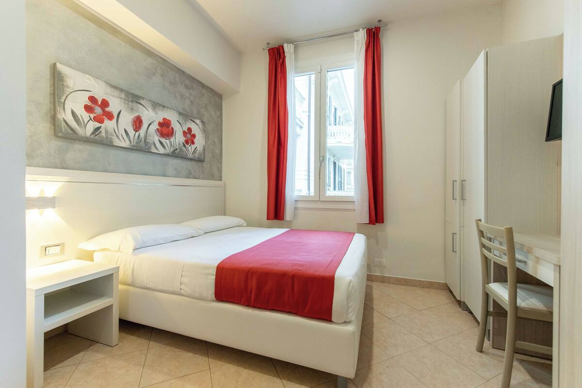 Un dormitorio con cama, mesita de noche y un cuadro en la pared.