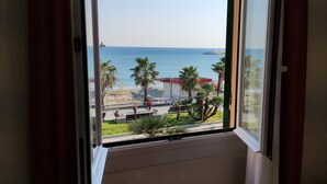 A view from a window overlooking a beach with palm trees and a clear sky. - Hotel Lido (Varazze)