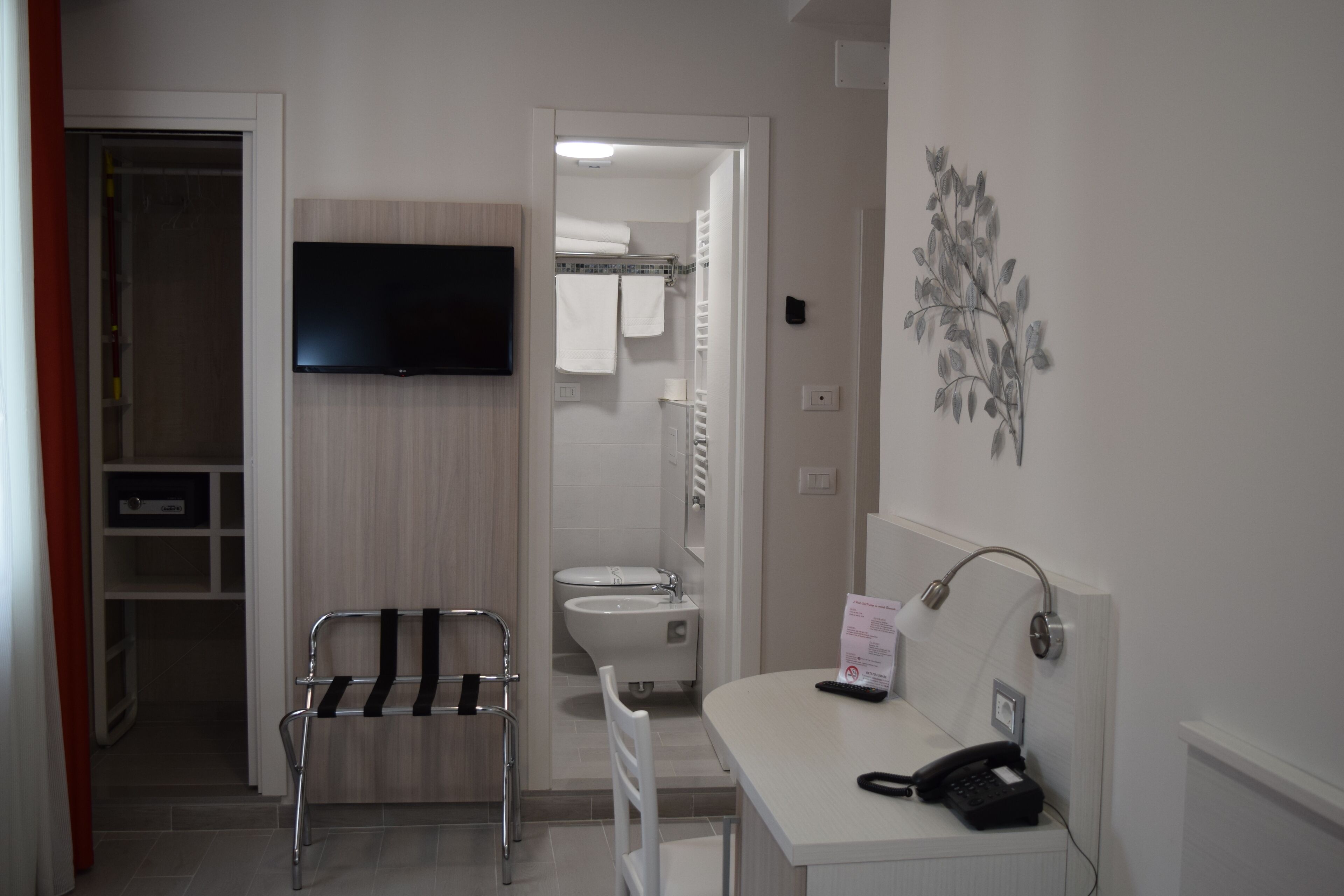 Une salle de bain d’hôtel équipée d’une douche, de toilettes et d’un lavabo. On y trouve également une chaise et un porte-serviettes.