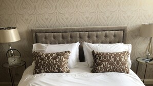 A neatly made bed with a patterned throw, a tufted headboard, and two bedside tables with lamps.