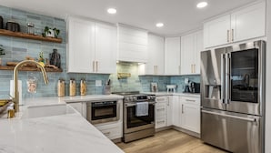 A modern kitchen with white cabinets, stainless steel appliances, and a marble countertop. - Del Mar Beach Club Condo with Ocean Views & Pool (Solana Beach)