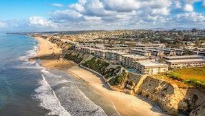 A coastal hotel with multiple buildings, a beach, and a cliffside. - Del Mar Beach Club Condo with Ocean Views & Pool (Solana Beach)