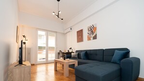 Uma sala de estar moderna com um sofá azul escuro, uma mesa de centro de madeira e um abajur.