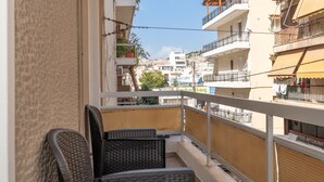 Varanda com cadeiras de vime, guarda-corpo e vista para edifícios vizinhos.