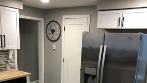 Eine moderne Küche mit einem Edelstahl-Kühlschrank, einer Holz-Arbeitsfläche und einer Uhr an der Wand.