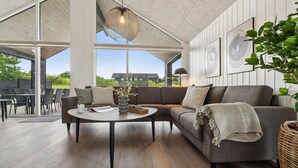 A modern living room with a sectional sofa, a round coffee table, and a hanging light fixture. - Nice home in Sydals with sauna (Sydals)