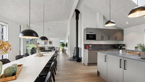A modern kitchen with a central island, pendant lighting, and a view to the living area. - Nice home in Sydals with sauna (Sydals)