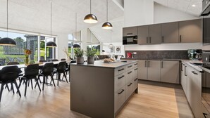 A modern kitchen with a central island, dark cabinets, and pendant lighting. - Nice home in Sydals with sauna (Sydals)